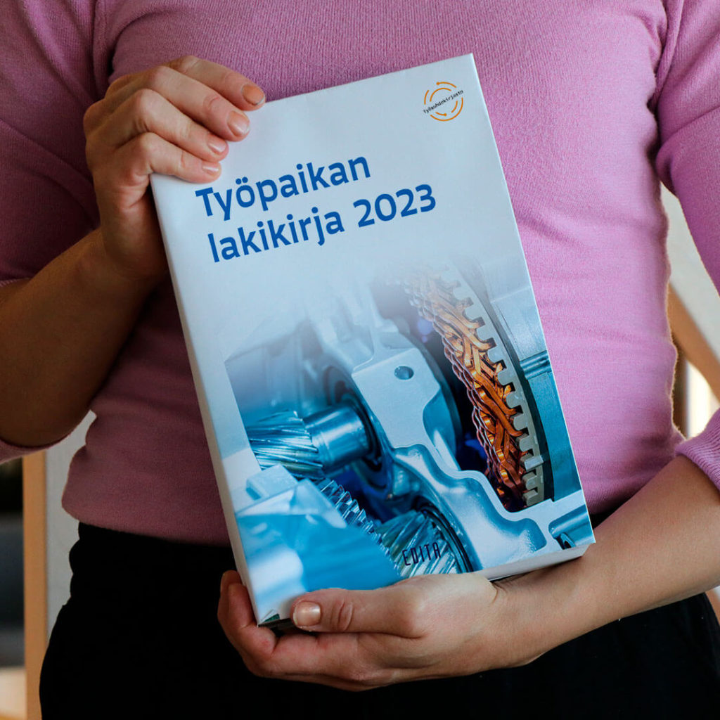Lähikuva henkilöstä, joka pitelee kirjaa Työpaikan lakikirja 2023.
